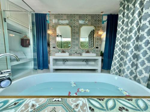 La salle de bains est pourvue d'une baignoire, de 2 lavabos et d'un miroir. dans l'établissement The Kiri Villas Resort, à Thalang