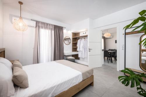 a white bedroom with a bed and a dining room at Nefeli's Apartment in Kardamaina