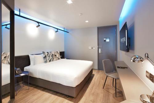 a bedroom with a bed and a desk and a chair at The Quarter Silom by UHG in Bangkok