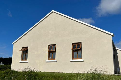a white house with four windows on the side of it at Achill Sound Holiday Village No 11 by Trident Holiday Homes in Achill Sound