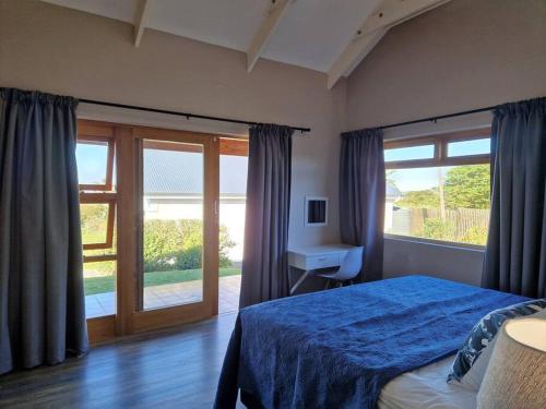 Un dormitorio con una cama azul y una ventana en HERON COTTAGE - for your seaside holiday. en Chintsa