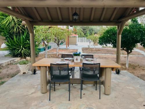 a wooden table and chairs under a pergola at Wooden Stories in Isthmia