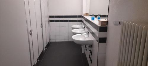 Baño con 3 lavabos y una fila de aseos en Kreuzlingen Youth Hostel, en Kreuzlingen