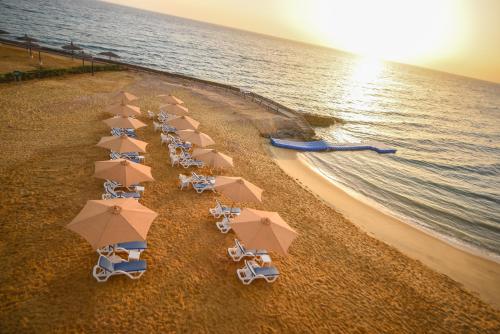 eine Gruppe von Stühlen und Sonnenschirmen am Strand in der Unterkunft Blumar El Dome Hotel in Ain Suchna