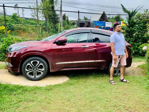 a man standing next to a red car at Miliya Guest House in Nuwara Eliya