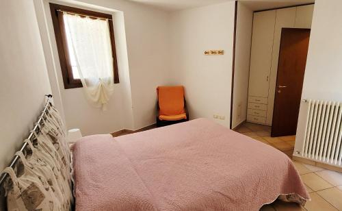 a bedroom with a bed and an orange chair at Lovely apartment in center of Barzio in Barzio