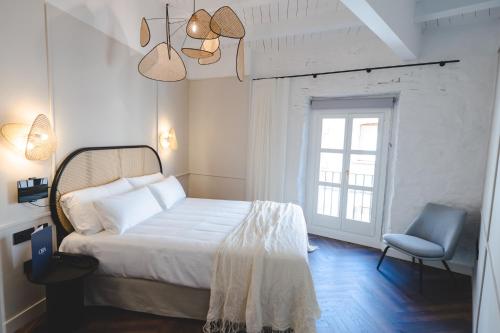 ein Schlafzimmer mit einem Bett, einem Stuhl und einem Fenster in der Unterkunft ORA Hotel Priorat, a Member of Design Hotels in Torroja