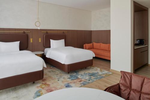 a hotel room with two beds and a couch at Movenpick Jumeirah Village Triangle in Dubai