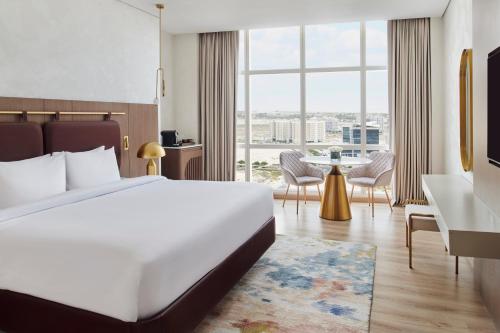a hotel room with a bed and a large window at Movenpick Jumeirah Village Triangle in Dubai