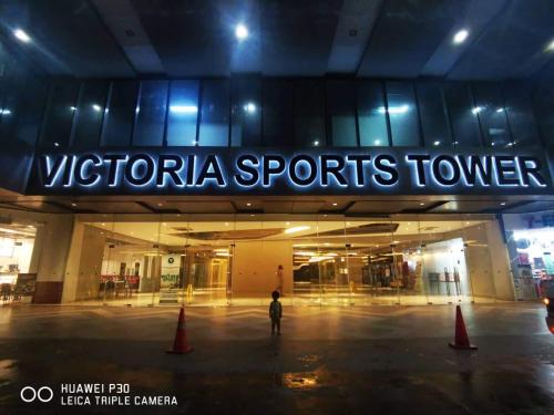 a person standing in front of a shopping center at night at Victoria Sports Tower - Cozy Ambiance Condo Unit in Manila