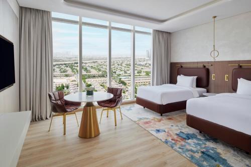 a hotel room with two beds and a table with chairs at Movenpick Jumeirah Village Triangle in Dubai
