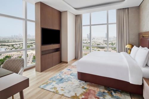 a hotel room with a bed and a large window at Movenpick Jumeirah Village Triangle in Dubai