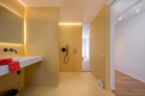 uma casa de banho com paredes amarelas, um lavatório e um chuveiro em Georges & Madeleine Apartments em Aalst