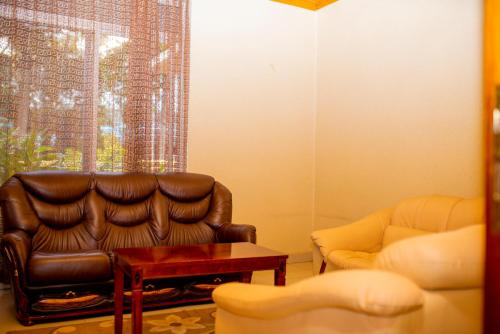 a living room with a leather chair and a table at The Garden Place Hotel in Ruhengeri