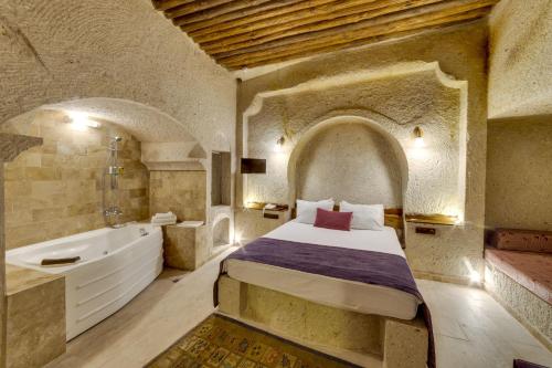 a bedroom with a bed and a tub and a sink at El Puente Cave Hotel in Ürgüp
