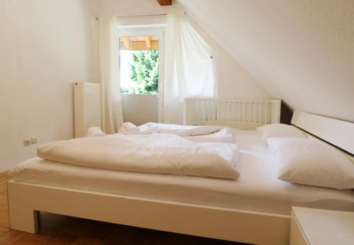 Cama blanca en habitación con ventana en Ferienwohnung Schneelehner, 2-Schlafzimmer, Feldberg, en Feldberg