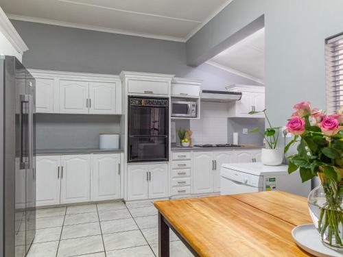 a kitchen with white cabinets and a wooden table at Hoogwater Family House in Wolseley