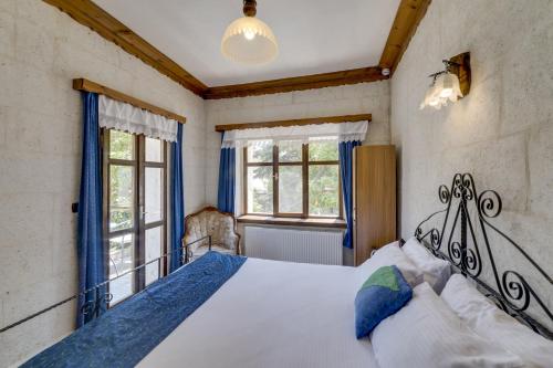 a bedroom with a large bed and two windows at El Puente Cave Hotel in Ürgüp