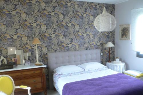 Saint-Yrieix-sur-Charenteにあるles kiwisのベッドルーム1室(紫の毛布と壁紙を使用したベッド1台付)