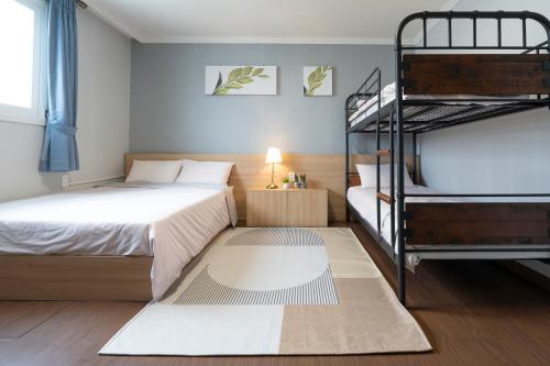 a bedroom with a bed and two bunk beds at Ellui Hotel Jeju in Jeju