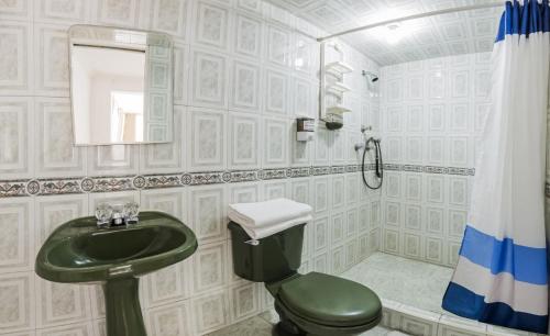 bagno con servizi igienici verdi e lavandino di Hotel Ecoinn a Bogotá