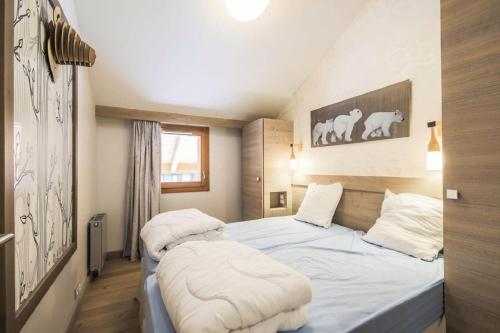 a bedroom with a bed with white sheets at Residence l Hevana - maeva Home in Méribel