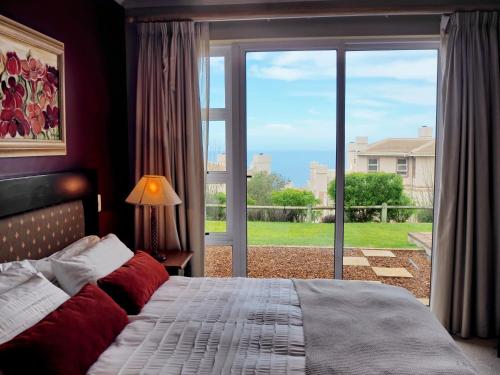 a bedroom with a bed and a large window at DunPuttin - Pinnacle Point Golf Estate in Mossel Bay