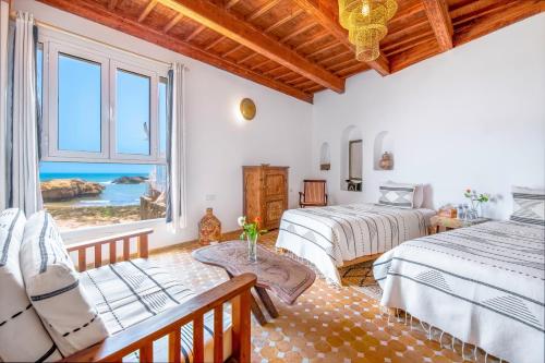 1 dormitorio con 2 camas y ventana en Riad Kafila en Essaouira