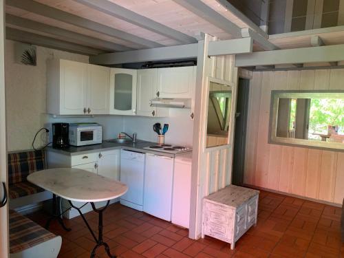 una pequeña cocina con armarios blancos y una mesa en les cabanes, en Lège-Cap-Ferret