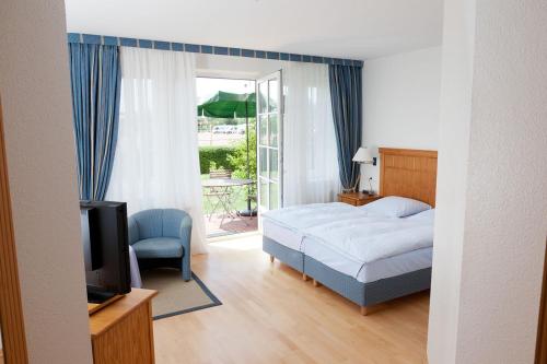 Schlafzimmer mit einem Bett, einem TV und einer Terrasse in der Unterkunft Hotel Altes Land in Jork
