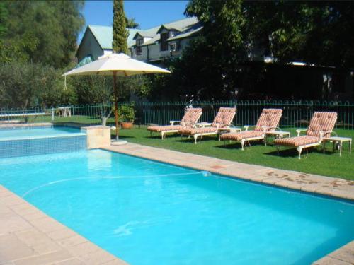 a group of chairs and an umbrella next to a swimming pool at Rainbow Glen Self Catering Chalets in Montagu