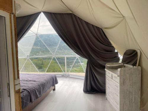 a bedroom with a bed and a large window at 4 seasons. 4 სეზონი Glamping Georgia Racha in Ambrolauri