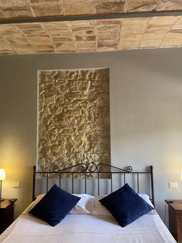 a bed with blue pillows in a bedroom with a stone wall at Casa Vacanze La Villetta in Montefranco