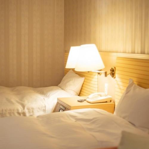 a hotel room with two beds and a lamp and a phone at Onahama Ocean Hotel & Golf Club in Iwaki