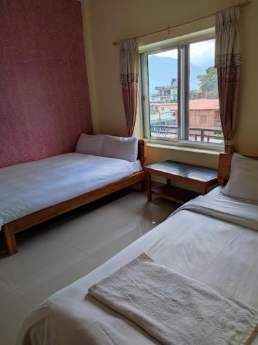 1 Schlafzimmer mit 2 Betten und einem Fenster mit Aussicht in der Unterkunft Hotel Green Hill View in Pokhara