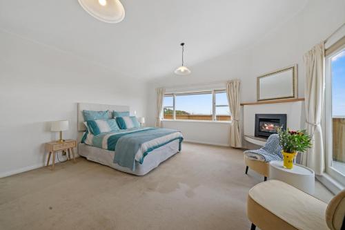 Kapiti Getaway - Paraparaumu Beach Rental في باراباراومو بيتش: غرفة نوم بسرير ومدفأة