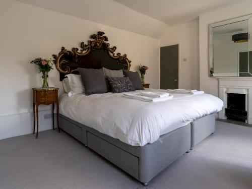 een slaapkamer met een groot bed met witte lakens en een open haard bij Pass the Keys Stunning 17th century 3 bedroom cottage in Chipping Campden