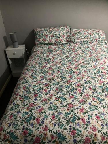 a bed with a floral comforter on it in a bedroom at Worthing bright and cosy double room in Worthing