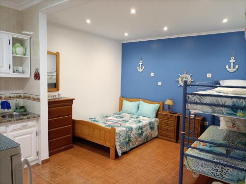 a bedroom with a bunk bed and a blue wall at Estúdio Mário Fanha in Nazaré