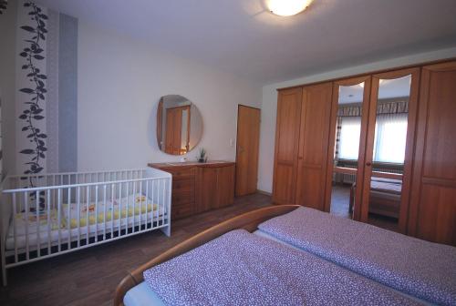 ein Babyzimmer mit einem Kinderbett und einem Spiegel in der Unterkunft Ferienhaus Irma 35530 in Uplengen