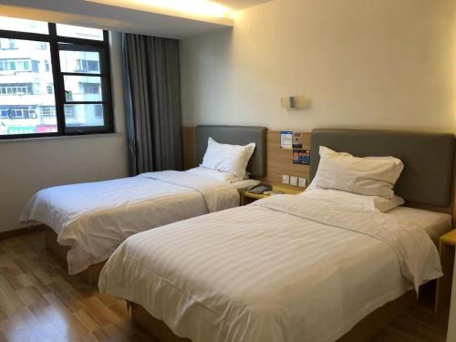 a hotel room with two beds and a window at 7Days Inn Anqing Train Station Branch in Anqing
