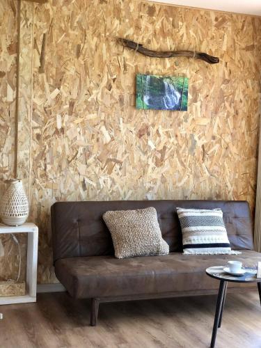 a brown couch in a living room with a wall at O REFUXIO DOS CEBREIROS in Mazaricos