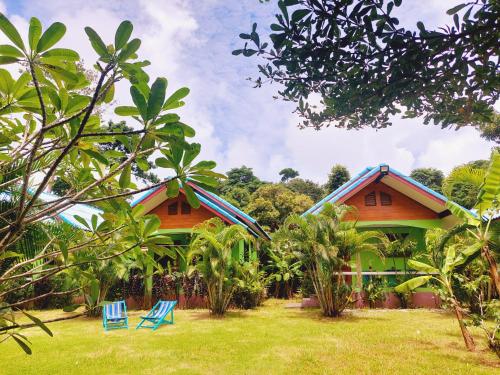 two houses with blue chairs in front of a yard at Papaya Cottage Koh Chang in Ko Chang