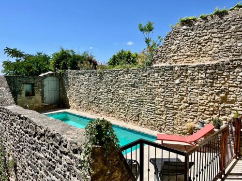 a pool in a stone wall with a table and a chair at La Villa 1777 in Lagnes