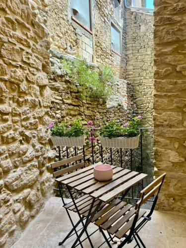 a wooden table and chairs next to a stone wall at La Villa 1777 in Lagnes