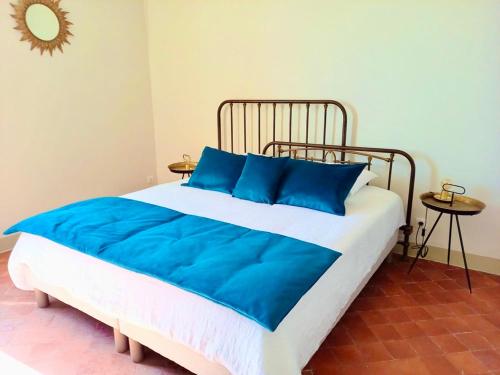 a bed with blue pillows in a room at La Villa 1777 in Lagnes