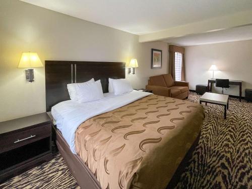 um quarto de hotel com uma cama grande e uma cadeira em Quality Inn & Suites Clemmons I-40 em Clemmons