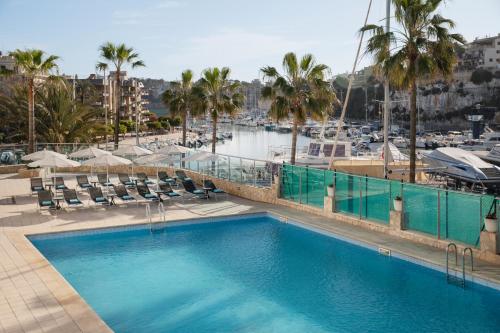 a large swimming pool with chairs and a marina at Porto Drach Aparthotel & Suites in Porto Cristo