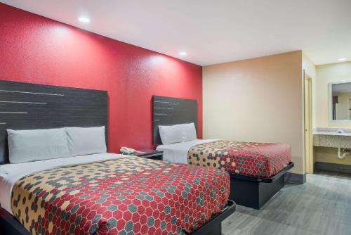 a hotel room with two beds and a red wall at Econo Lodge Lake Charles University Area in Lake Charles