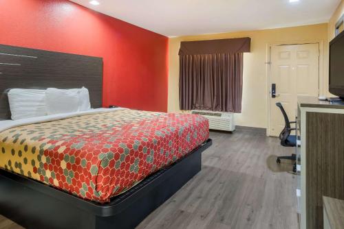 a hotel room with a bed and a red wall at Econo Lodge Lake Charles University Area in Lake Charles